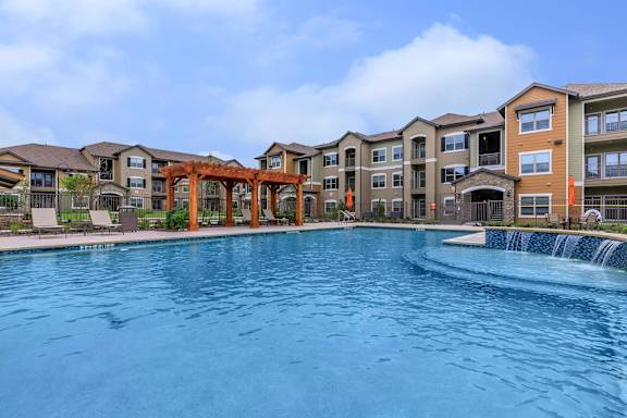 a large swimming pool with an apartment building in the background at Cypress Creek at Hazelwood Street, Texas, 75407