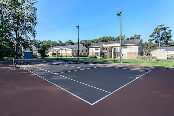 an empty tennis court with apartments in the background