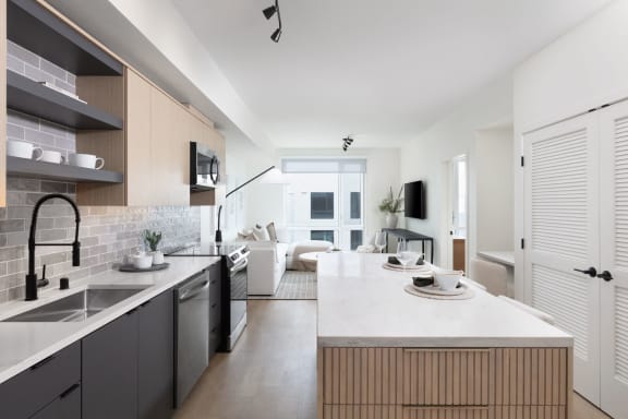 a kitchen and living room with a white counter top and a sink