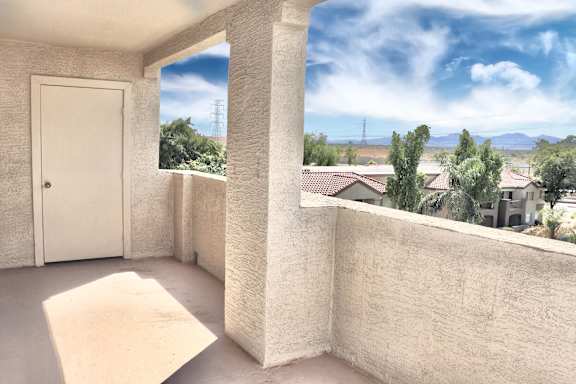 A balcony with a door and a window overlooking a residential area.
