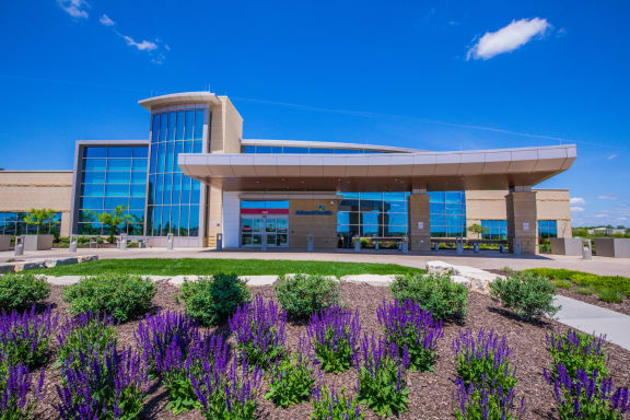 a building with purple flowers in front of it at The Residences at Bluhawk Apartment Homes, Overland Park, Kansas