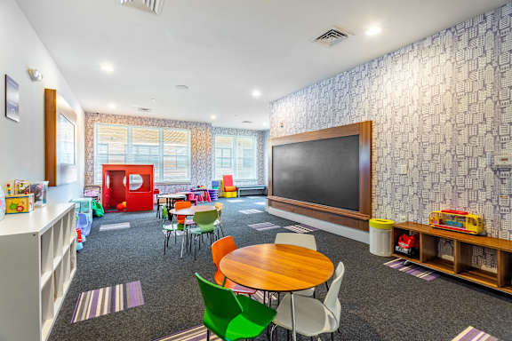 a childrens room with a tv and tables and chairs