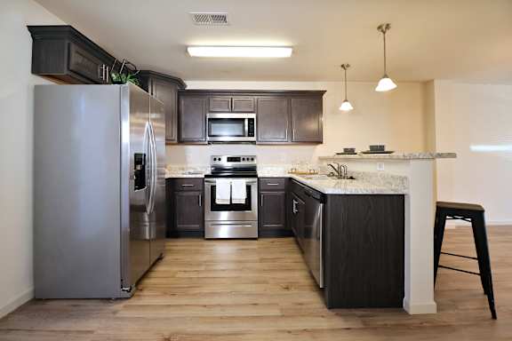 A modern kitchen with dark wood cabinets and stainless steel appliances.
