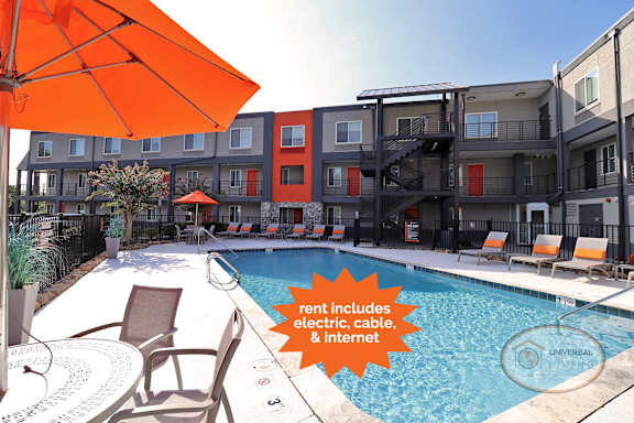 a pool with an orange umbrella in front of an apartment building