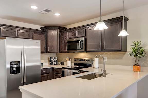 A modern kitchen with dark brown cabinets and stainless steel appliances.