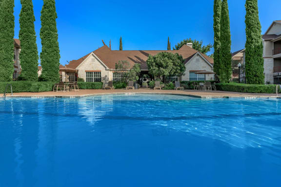 a large swimming pool with a house in the background
