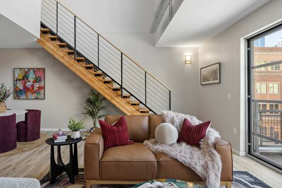 A living room with a brown couch and a staircase.