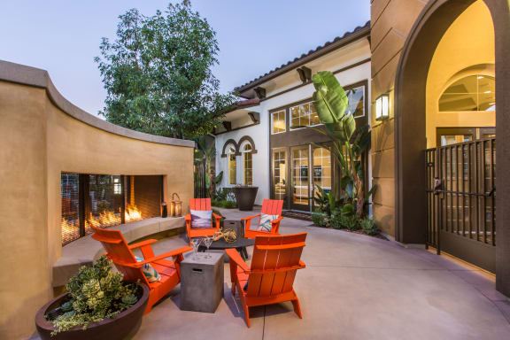 a patio with orange chairs and a table in front of a house at Capriana at Chino Hills, Chino Hills, CA
