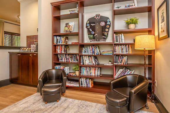 A room with a bookshelf and two chairs.