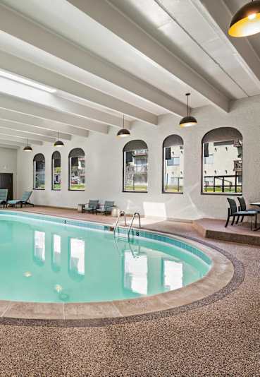 A large indoor swimming pool with a brown floor and white walls.