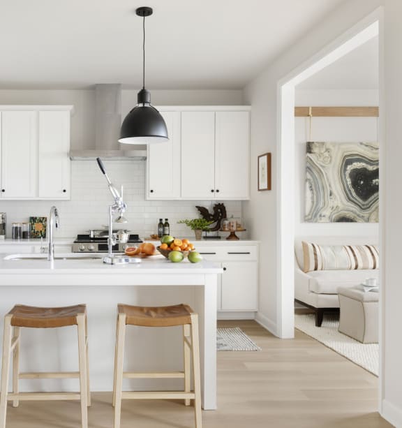 a kitchen with white cabinets and a white island with three stools