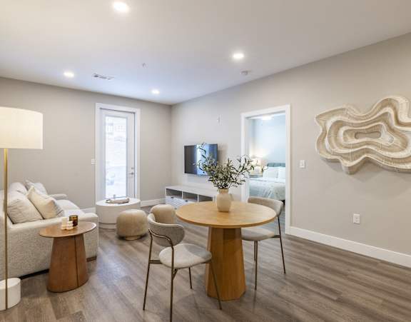 A living room with a white couch, a wooden coffee table, and a large abstract art piece on the wall.
