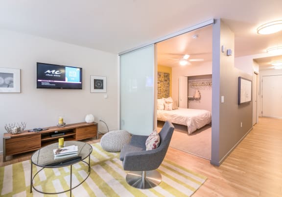 a living room with a table and two chairs and a bedroom with a tv