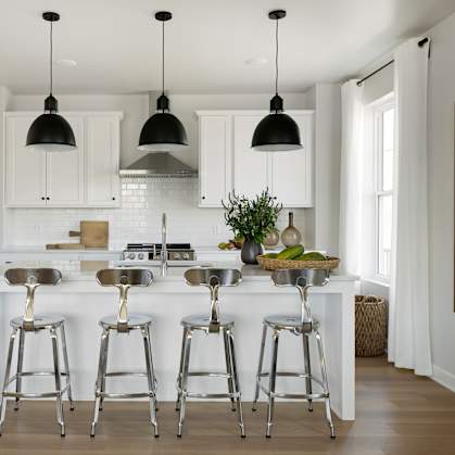 a kitchen with white cabinets and a white island with bar stools