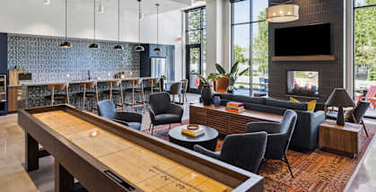 the lobby of a hotel with a communal table and a fireplace