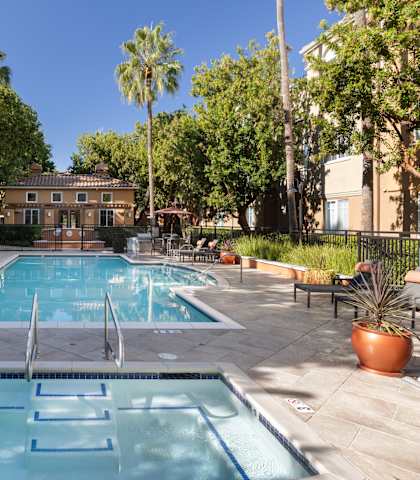 A pool surrounded by trees and chairs.