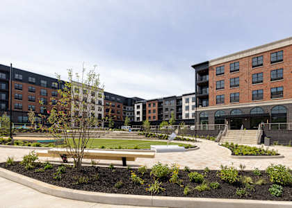 A courtyard with a bench and a tree in front of apartment buildings.