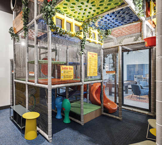 a childrens play area with a playhouse and a set of plastic chairs and