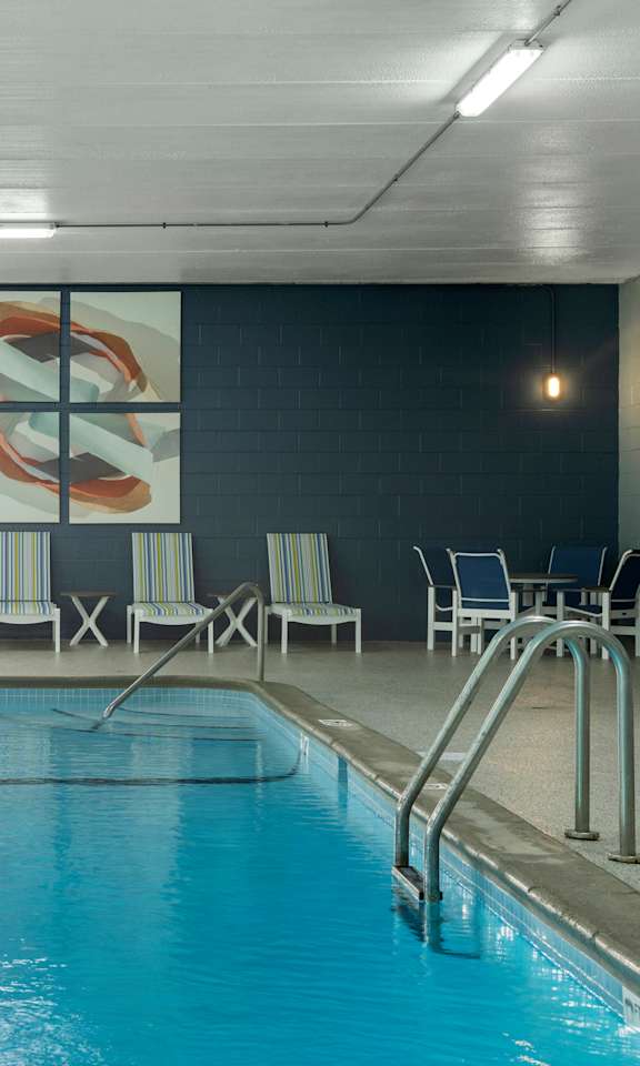 A swimming pool with a metal ladder and chairs around it.