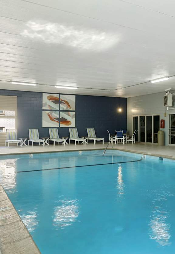 A large indoor swimming pool with lounge chairs and a mural on the wall.