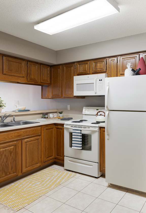 a kitchen with white appliances and wooden cabinets  at The Kendrick, Minnesota