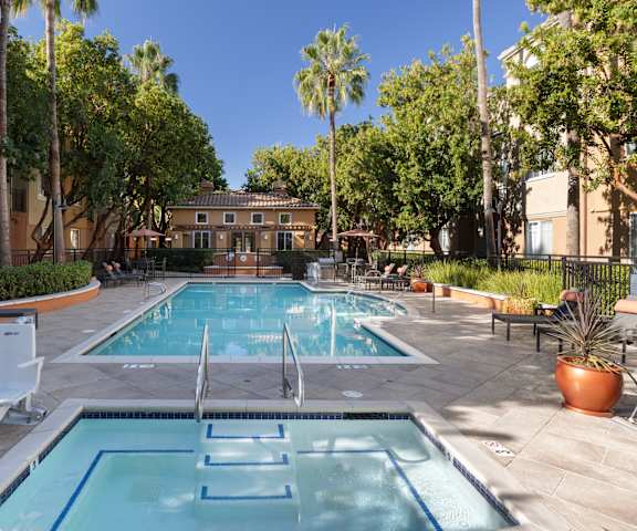 A pool surrounded by trees and chairs.