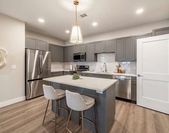 A modern living room with a television, sofas, and a kitchen in the background at Preserve at Sycamore Creek, Osage Beach, Missouri