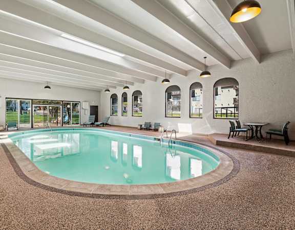 A large indoor swimming pool with a brown floor and white walls.