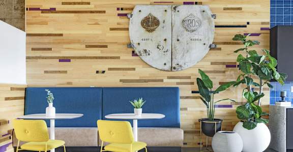 a seating area with yellow chairs and tables and a wooden wall