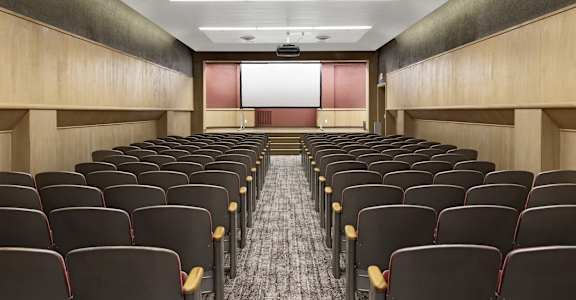a room filled with rows of chairs in front of a projector screen in a classroom