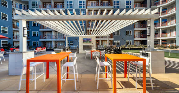 A patio with orange chairs and tables is in front of a building at The Rey Downtown, Phoenix, 85003