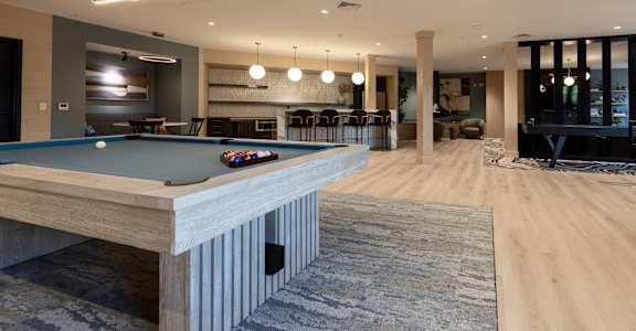 A pool table is in the middle of a room with a wooden floor.