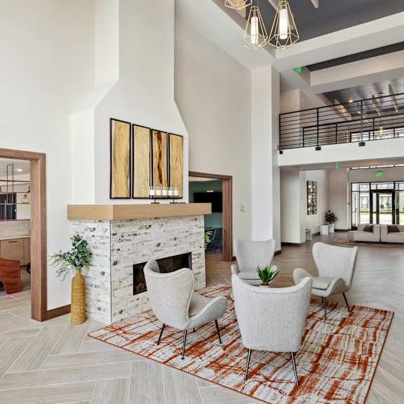a living room with a couch table and chairs and a kitchen in the background