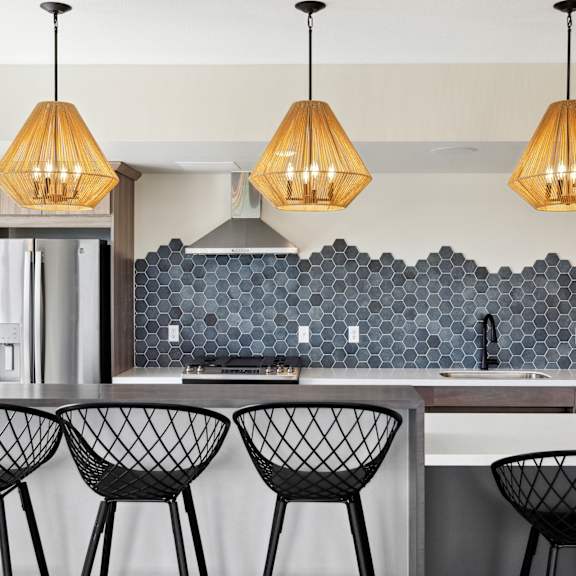 A kitchen with a white counter and black chairs.