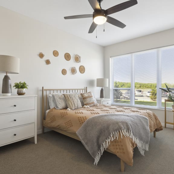 a bedroom with a large window and a ceiling fan
