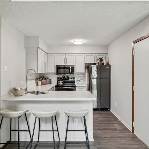 A bedroom with a large bed, a white dresser, and a round mirror on the wall. at Seasons Villas Apartments, Woodbury, MN