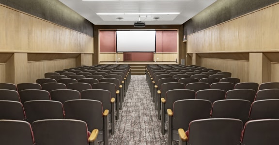 a room filled with rows of chairs in front of a projector screen in a classroom