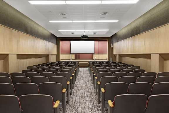 a room filled with rows of chairs in front of a projector screen in a classroom