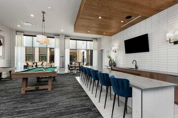 A room with a pool table and a bar area.