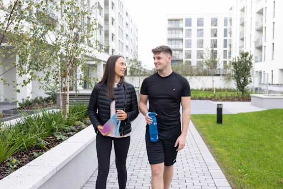 a man and a woman walking down a sidewalk holding water bottles
