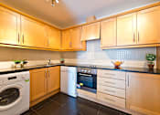 Thumbnail 1 of 6 - a kitchen with wooden cabinets and white appliances and a washing machine