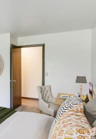 a bedroom with a bed and a chair and a window