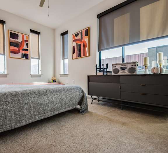 A room with a bed, a cabinet, and two windows.