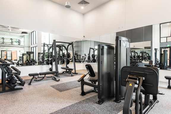 A gym with a variety of equipment including treadmills, weights, and exercise machines.