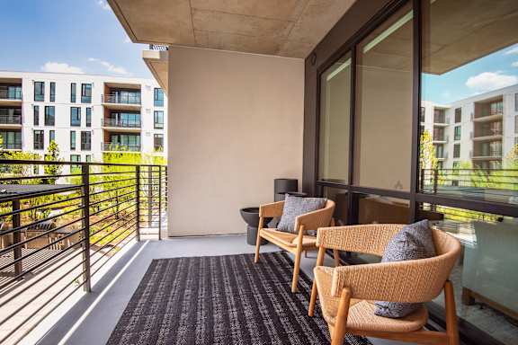 A balcony with two chairs and a table.