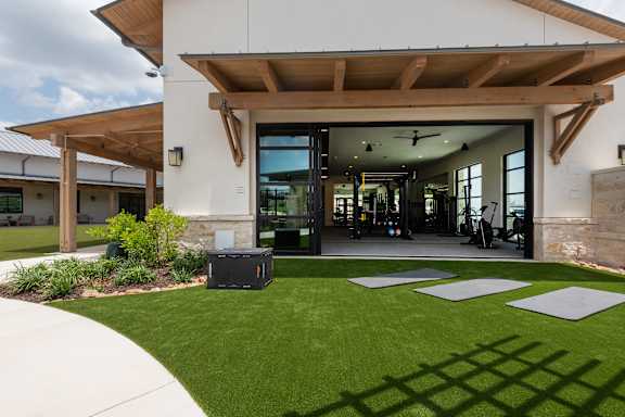A modern house with a large front yard and a covered patio area.