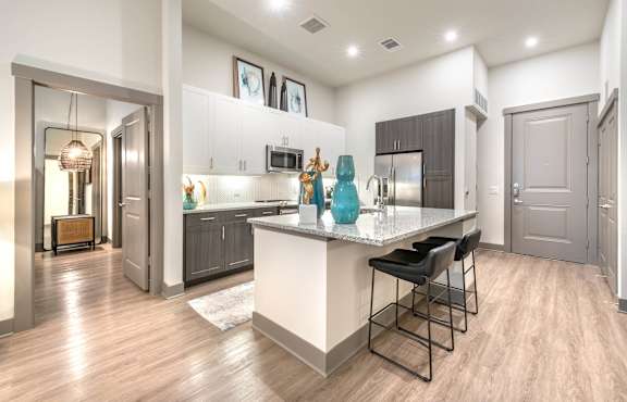 A modern kitchen with a bar stool and a fridge.at The Bridge at McKinney, McKinney, TX