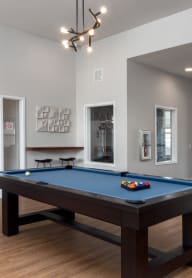 a pool table in a clubhouse with a door to a patioat The Station St. Peters, St. Peters, MO 63376