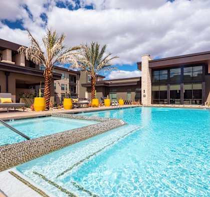 A large swimming pool in front of a building with palm trees.