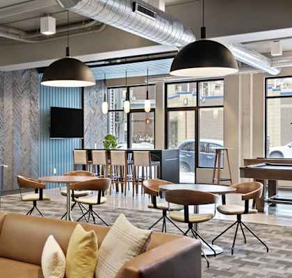 A modern office lounge with brown leather sofas and yellow cushions.